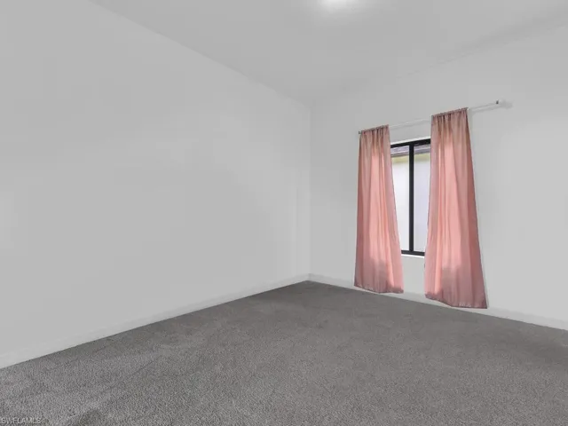 Spare room featuring carpet flooring and baseboards