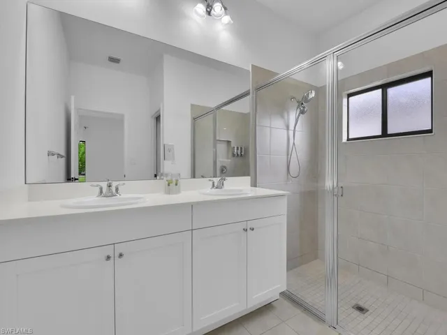 Bathroom featuring double vanity, a shower stall, and light tile patterned flooring