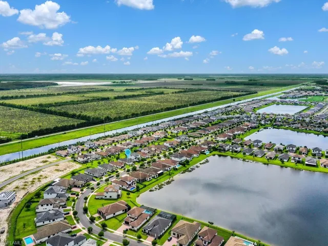 Aerial perspective of suburban area featuring a nearby body of water and farmland