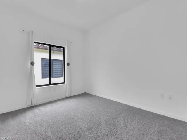 Unfurnished room featuring light carpet and baseboards