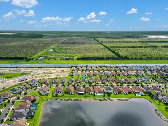 Aerial view of residential area with a nearby body of water and large plots for crops