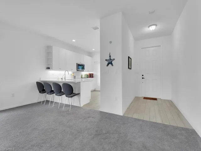 Kitchen featuring light countertops, open shelves, white cabinetry, a peninsula, and a kitchen breakfast bar