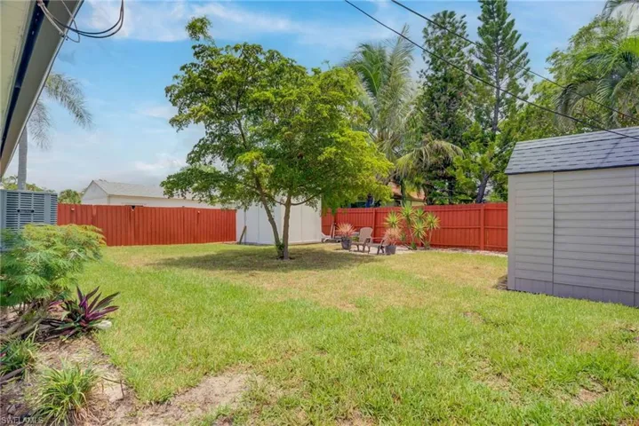 Fenced backyard featuring a storage unit