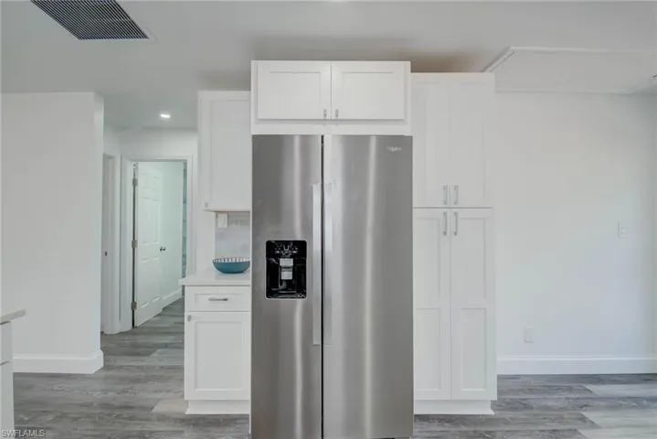 Kitchen with stainless steel refrigerator with ice dispenser, white cabinets, and recessed lighting