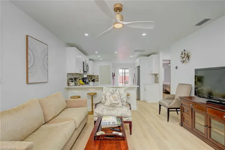 Living area featuring light wood-style floors, a ceiling fan, and recessed lighting