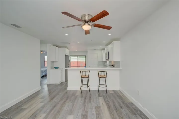 Kitchen with white cabinets, a peninsula, light wood finished floors, ceiling fan, and recessed lighting