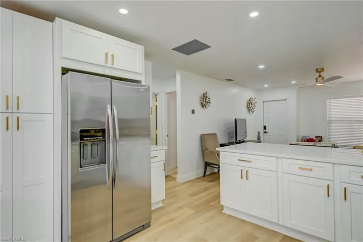Kitchen featuring stainless steel refrigerator with ice dispenser, white cabinetry, light wood-style flooring, recessed lighting, and light countertops