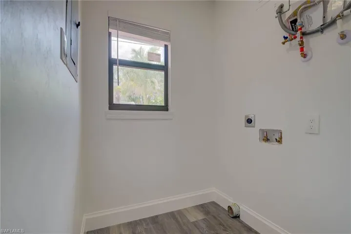 Laundry room with hookup for an electric dryer, hookup for a washing machine, and dark wood-type flooring