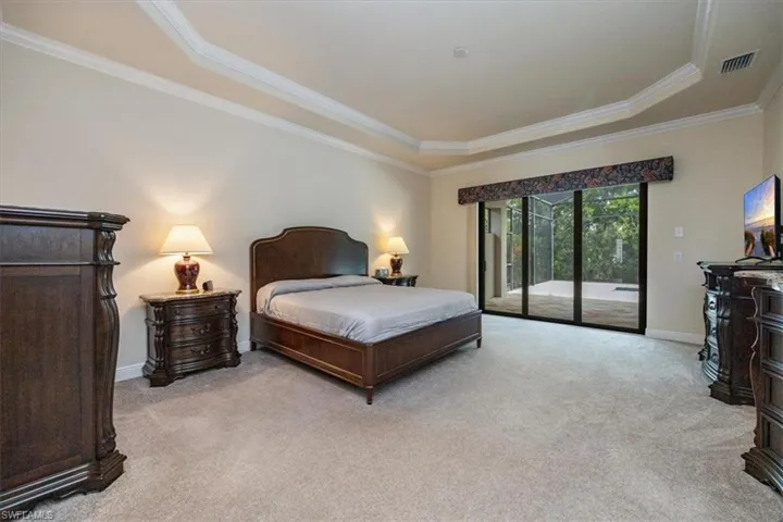 Bedroom with access to exterior, light colored carpet, and ornamental molding