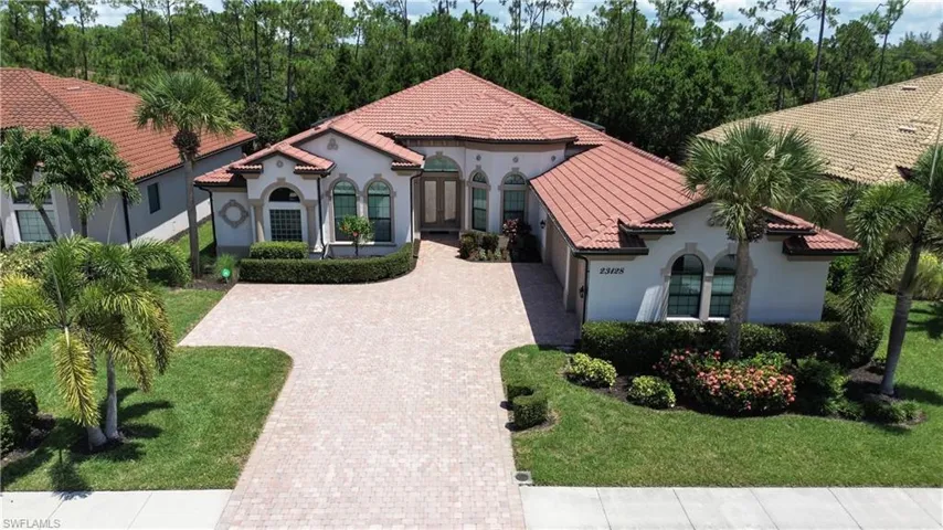 Mediterranean / spanish-style house with decorative driveway, stucco siding, a tile roof, and a front yard