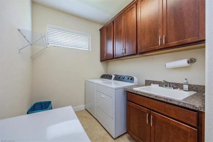 Laundry area with independent washer and dryer, cabinet space, and light tile patterned floors