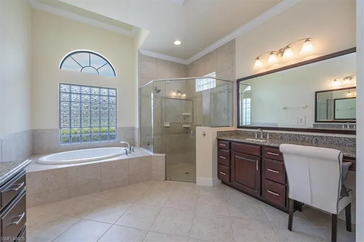 Bathroom featuring vanity, ornamental molding, a garden tub, a shower stall, and tile patterned flooring
