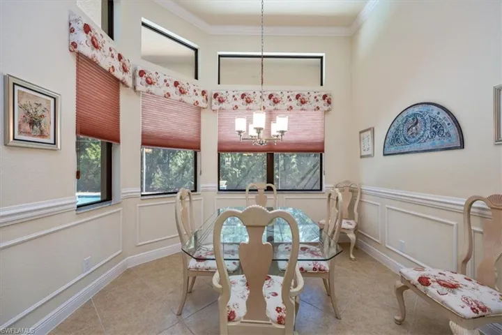 Dining area with tile patterned flooring, ornamental molding, and a chandelier
