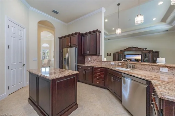 Kitchen featuring arched walkways, crown molding, tasteful backsplash, stainless steel appliances, and light stone countertops
