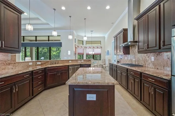 Kitchen featuring tasteful backsplash, crown molding, a center island, dark brown cabinetry, and wall chimney exhaust hood