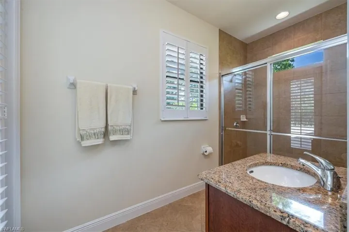 Bathroom featuring vanity, tiled shower, tile patterned floors, and recessed lighting