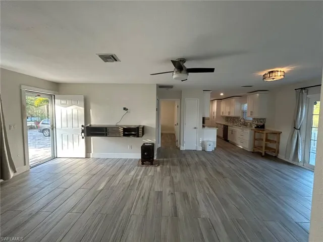 Living area with plenty of natural light, light wood-style floors, and a ceiling fan