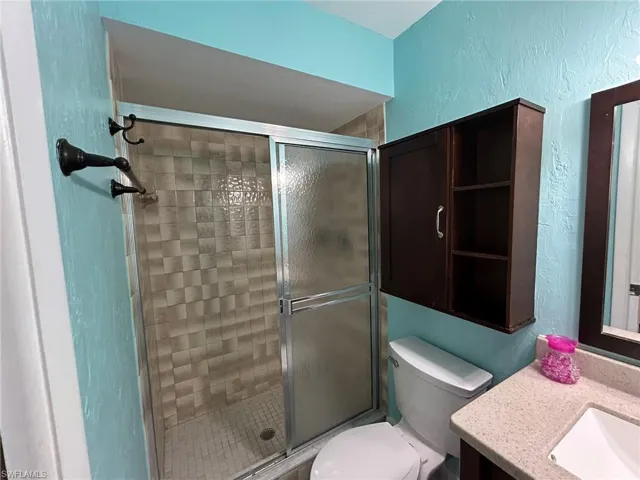 Full bath with a textured wall, vanity, and a stall shower