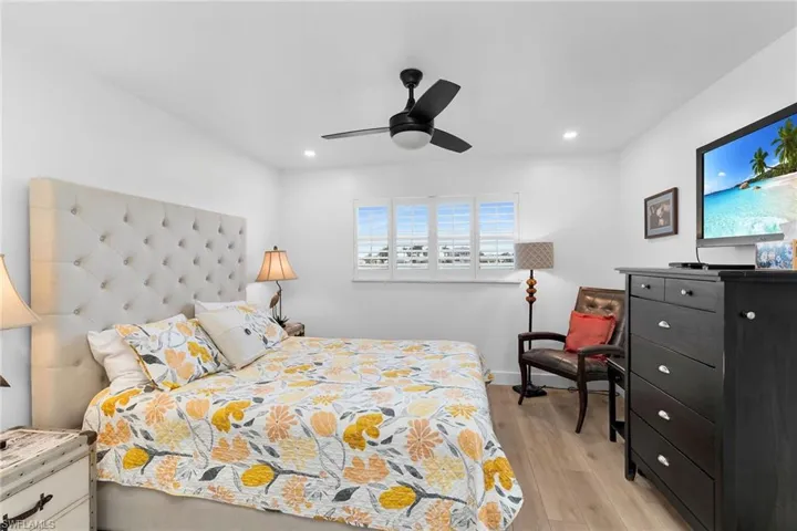 Primary bedroom with light wood-type flooring, ceiling fan, and recessed lighting