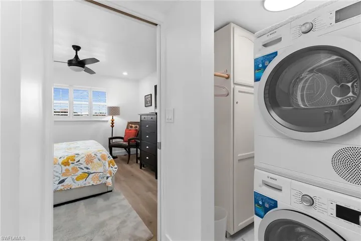 Laundry area featuring light wood-type flooring, stacked washer / dryer, cabinet space, in thePprimary Suite
