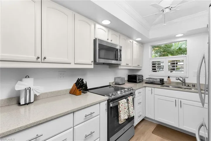 Kitchen featuring crown molding, stainless steel appliances, white cabinetry, ceiling fan, and recessed lighting