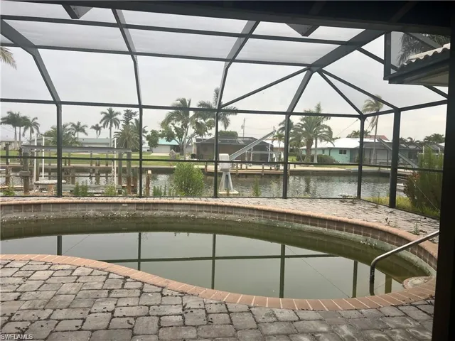 Outdoor pool featuring glass enclosure, a water view, and a boat dock