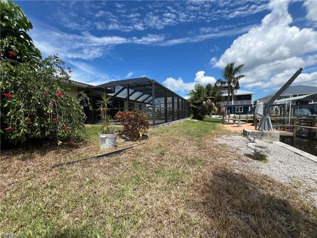 View of green lawn featuring a lanai, pool and dock w/ lift