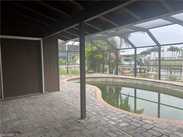 Outdoor pool with a water view, a patio, and glass enclosure