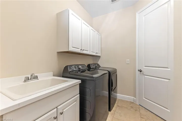 Laundry/Storage area with cabinet space and washer and clothes dryer and entrance between the house and attached garage.