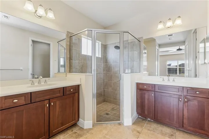 Primary Bathroom with large walk-in shower, two vanities, tile floors, and seperate toilet area.