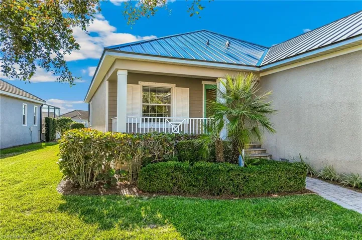 Entrance to property with a metal roof, covered porch, landscaped yard, and walkway to front door.