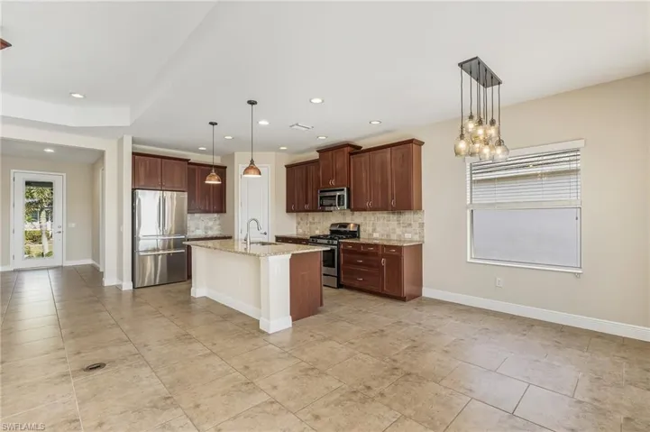 Large Kitchen with stainless steel appliances, light granite counters, tasteful backsplash, large kitchen island with sink, panty, and recessed and hanging lights.