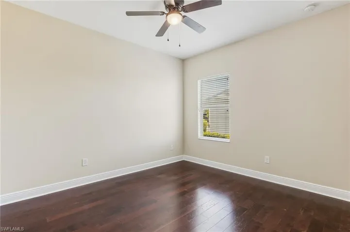 Second Guest bedroom featuring dark wood-style laminate floors, ceiling fan, and closet.