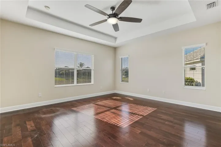 Large master bedroom overlooking the lake. Featuring a raised/tray ceiling, dark wood-type laminate flooring, ceiling fan, ensuite bath, and two walk-in closets.