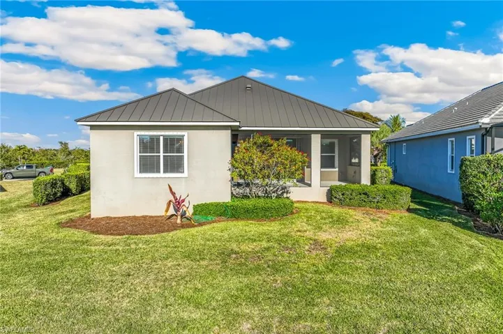 Rear view of property with lawn and landscaped area.