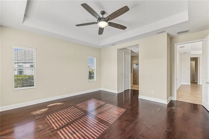 Large master bedroom overlooking the lake. Featuring a raised/tray ceiling, dark wood-type laminate flooring, ceiling fan, ensuite bath, and two walk-in closets.