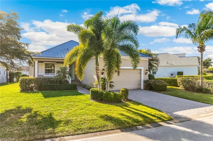 View of front of home featuring a front lawn, a metal roof, decorative driveway, covered porch, and an attached 2 car garage