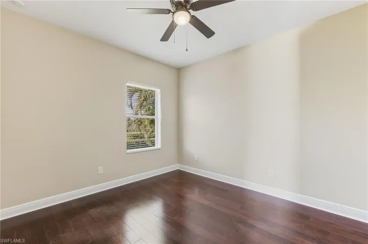 Guest bedroom featuring dark wood-style laminate floors, ceiling fan, and closet.