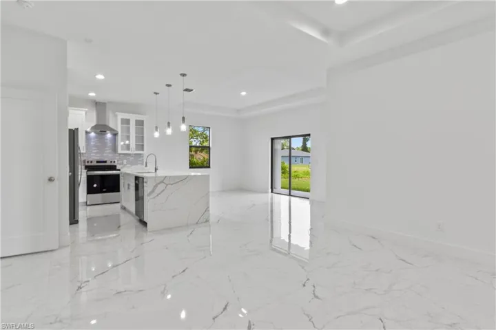 Unfurnished living room featuring light marble finish flooring, a tray ceiling, and recessed lighting
