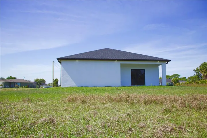 View of the back of property featuring a shingled roof and stucco siding