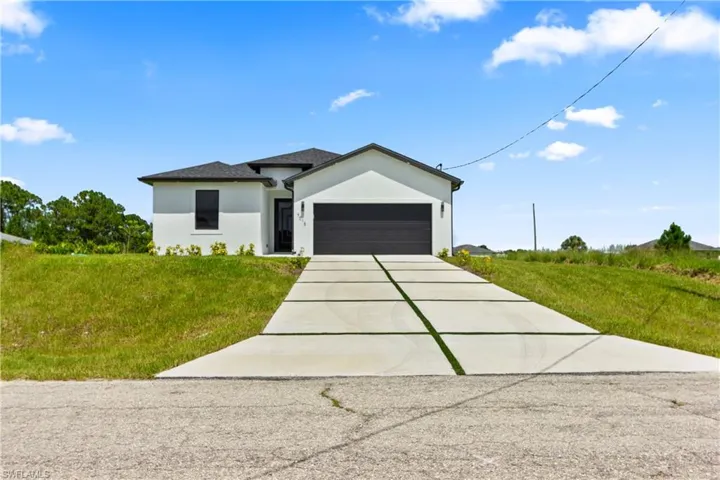 View of front of house with driveway, a garage, stucco siding, and a front yard