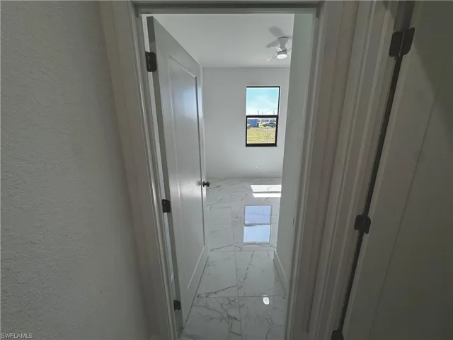 Second bedroom doorway featuring marble finish floor and a textured wall