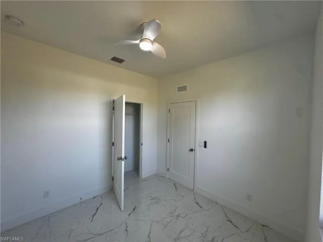 Second bedroom with a ceiling fan, marble finish floor, visible vents, and baseboards