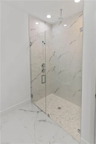 Bathroom with a marble finish shower, marble finish floors, and recessed lighting