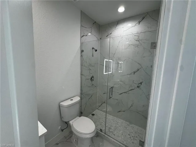 Master bathroom featuring a marble finish shower, baseboards, toilet, marble finish floor, and vanity