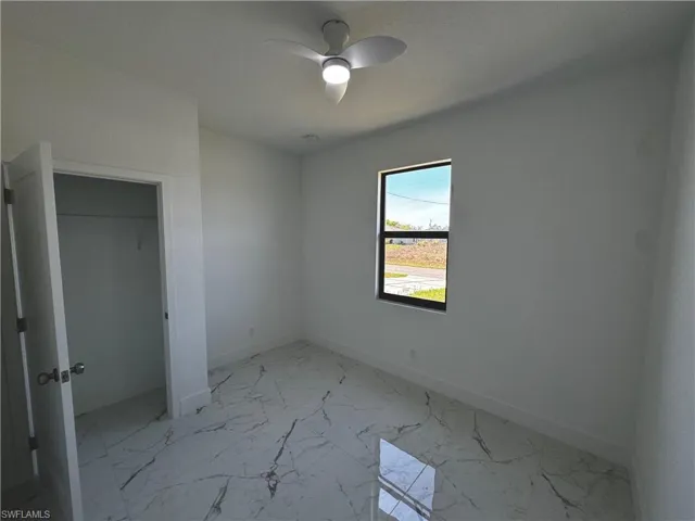 First bedroom with marble finish floor, baseboards, and a ceiling fan