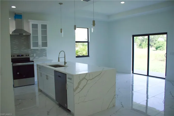 Kitchen featuring black dishwasher, white cabinets, wall chimney exhaust hood, glass insert cabinets, and stainless steel range with electric cooktop