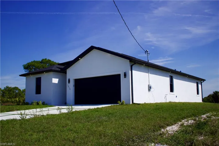 View of side of home with an attached garage, a yard, and stucco siding