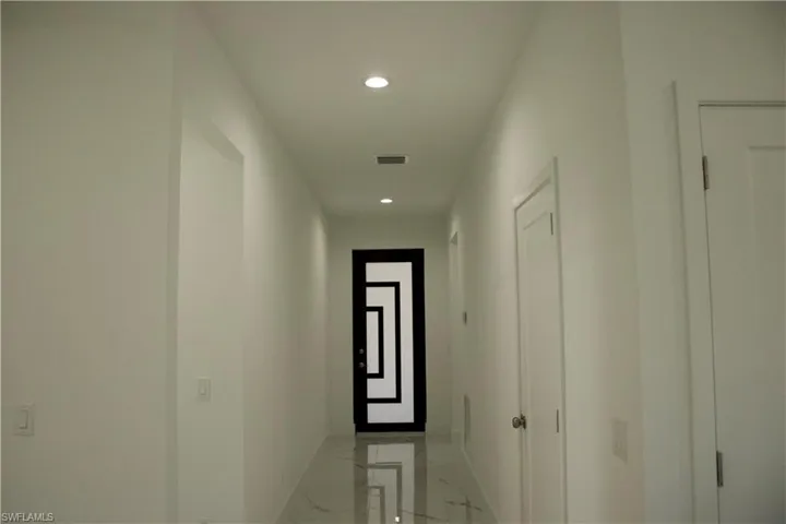Hallway with marble finish floor, visible vents, and baseboards