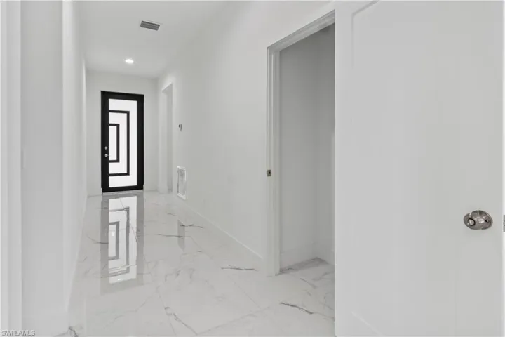 Hallway featuring light marble finish flooring and recessed lighting